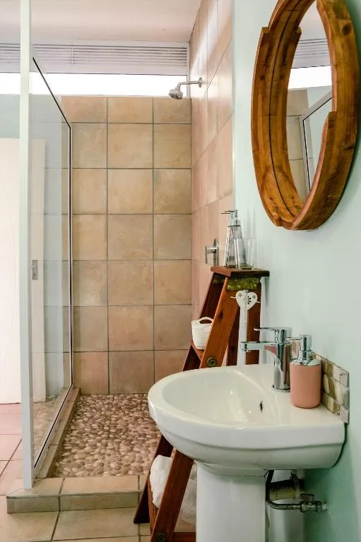 Modern bathroom with walk-in shower, pedestal sink, and wooden mirror frame