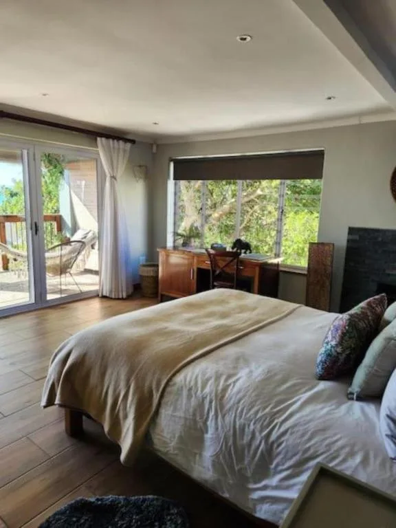 Spacious bedroom with bed, desk area, and large windows overlooking forest