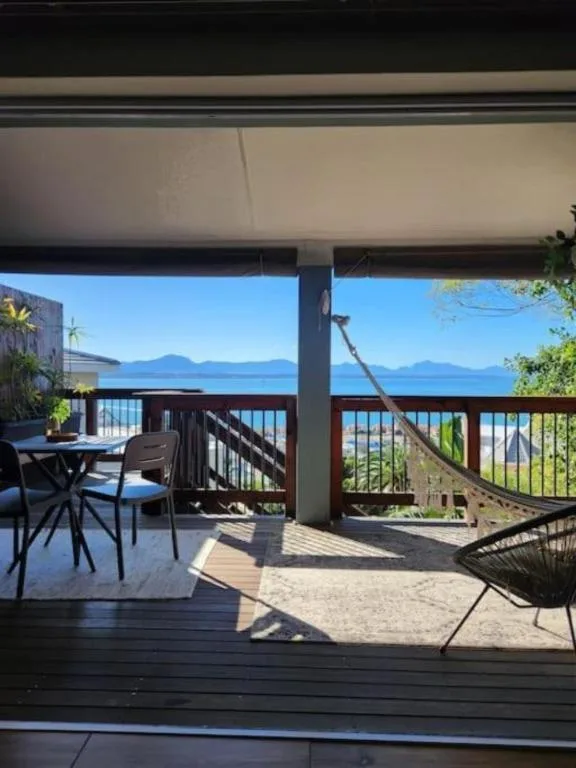 Spacious covered deck with ocean and mountain views, dining table and seating