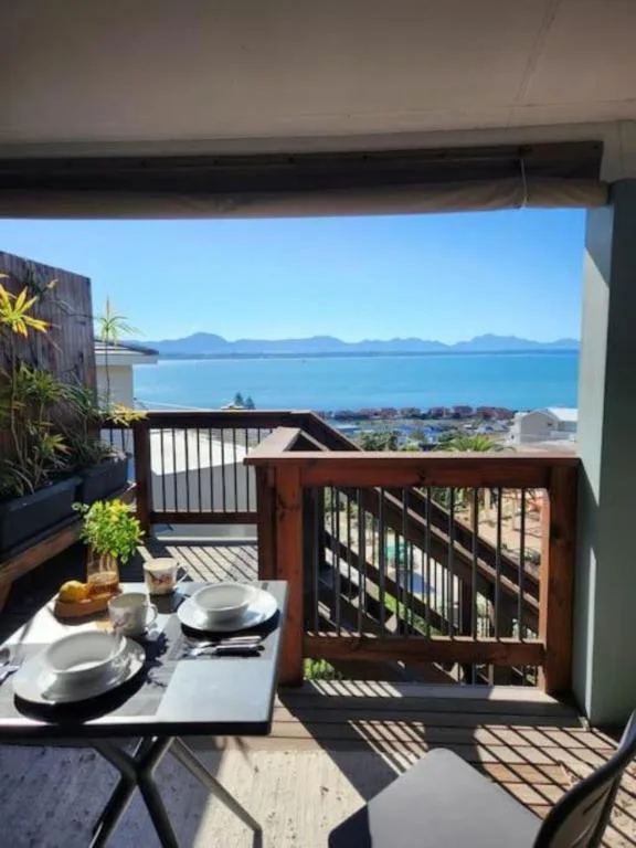 Outdoor deck with dining table overlooking bay and mountains in distance