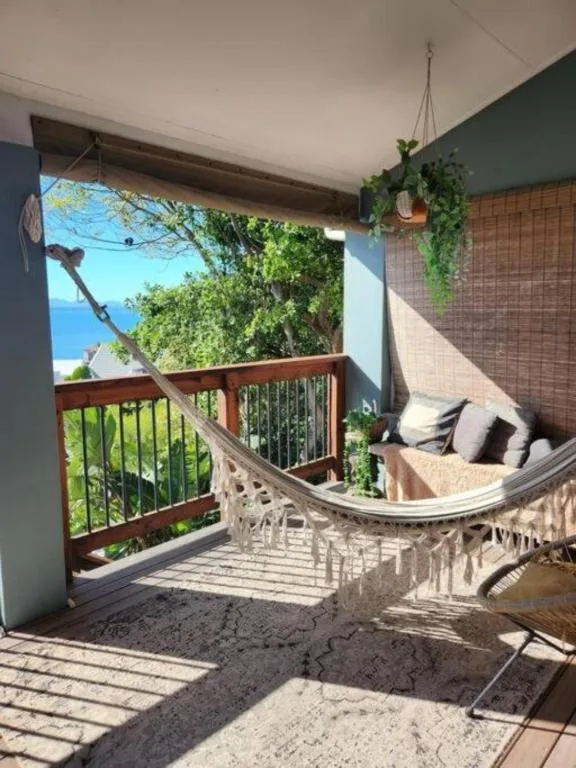 Shaded ocean-view deck with hammock, hanging plants, and wooden railings