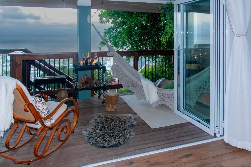 Expansive wooden deck with ocean view, hammock, and outdoor seating