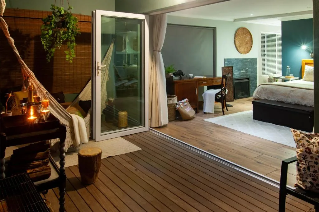 Wooden deck with hammock, string lights, and sliding doors to bedroom