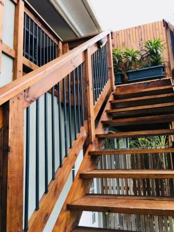 Wooden staircase with metal railings leading to upper deck area