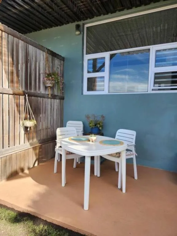 Covered patio with white dining table and chairs overlooking garden