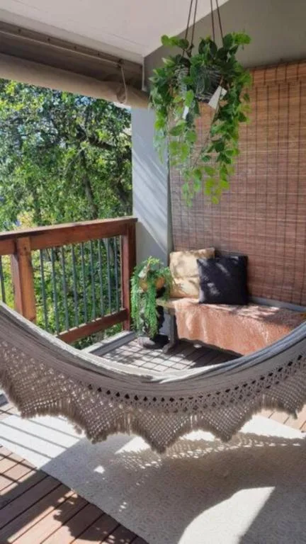 Cozy covered deck with hanging plants, cushioned seating, and garden views
