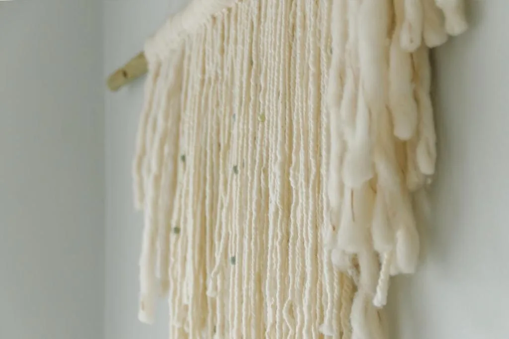 Close-up of cream-colored macramé wall hanging with decorative knotwork details