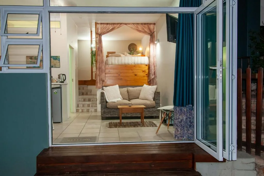 Open-plan lounge with sofa, wooden coffee table, and bedroom visible beyond