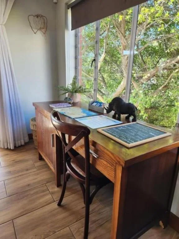 Modern workspace with desk, chairs, and lush green views through large windows