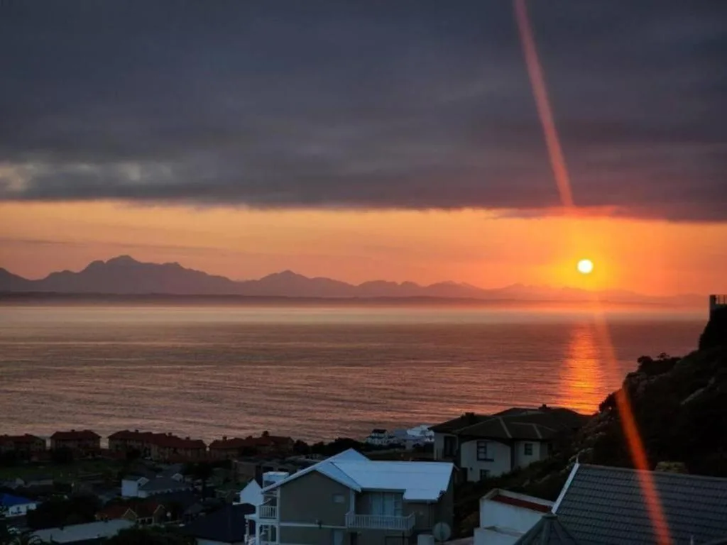 Stunning sunset over ocean with mountains silhouetted against golden sky