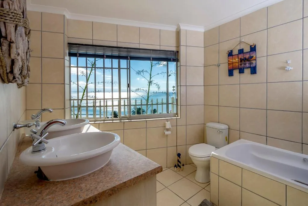 Bathroom with basin, toilet, bathtub, and scenic water views through window