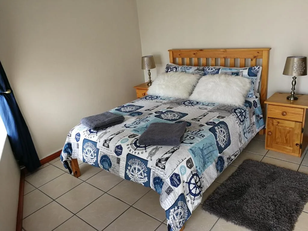 Spacious bedroom with wooden bed frame and nautical bedding, matching nightstands