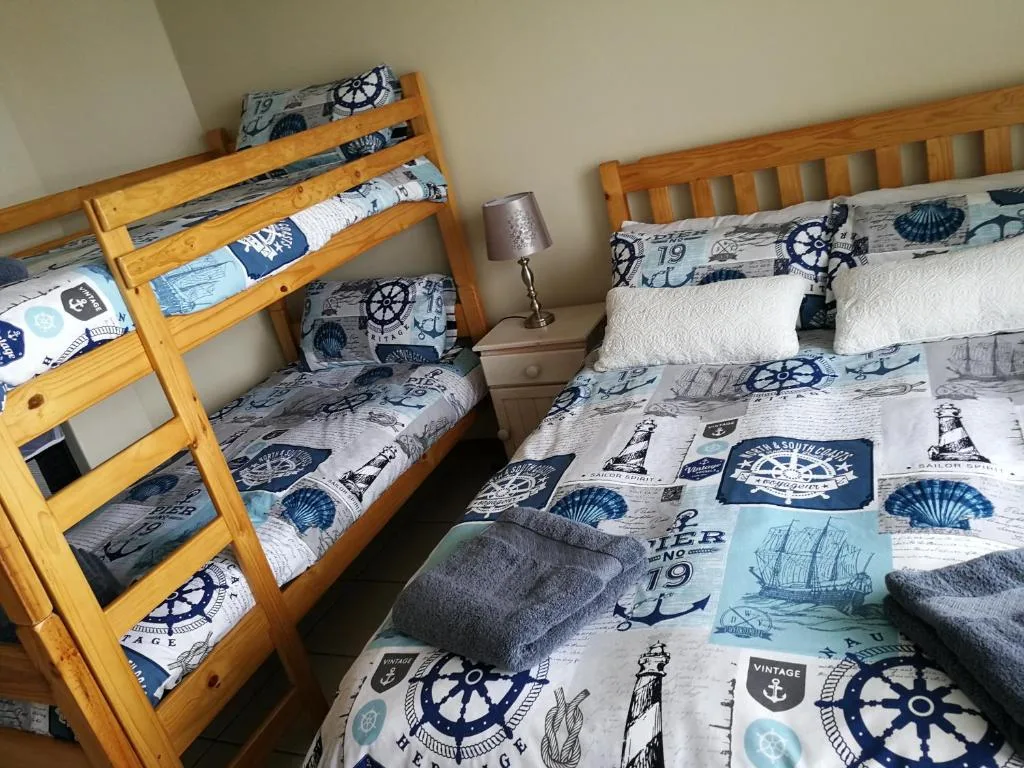 Bedroom with wooden bunk bed and nautical-themed bedding and pillows
