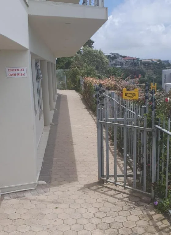 Paved outdoor pathway with metal railing and coastal town views below