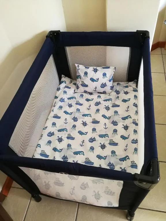 Portable travel crib with marine-themed bedding and pillows