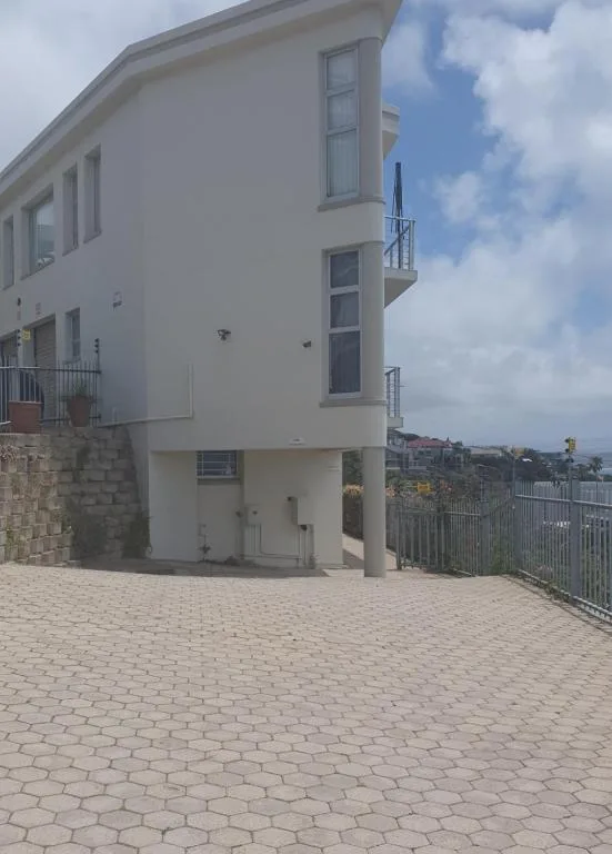 White modern apartment building with paved driveway and metal railing