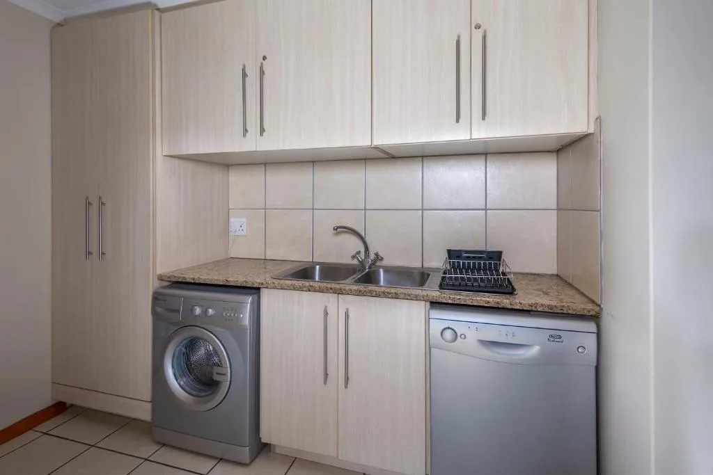 Modern kitchen with light wood cabinetry, granite countertop, stainless steel sink and appliances