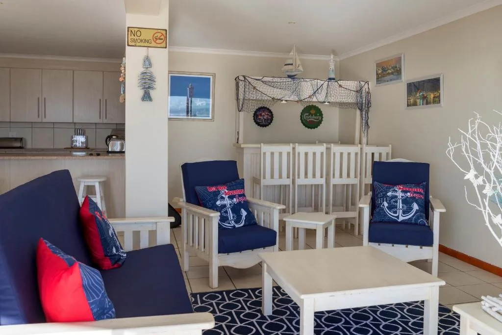 Coastal-themed living room with navy chairs, nautical decor, and ocean views