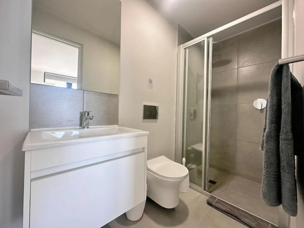 Modern bathroom with white vanity, toilet, and glass shower enclosure