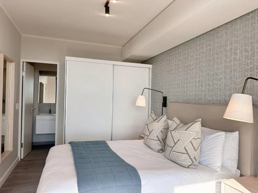 Modern bedroom with queen bed, patterned pillows, and ensuite bathroom access