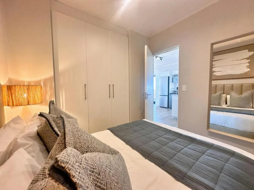 Modern bedroom with queen bed, built-in wardrobes, and ensuite access