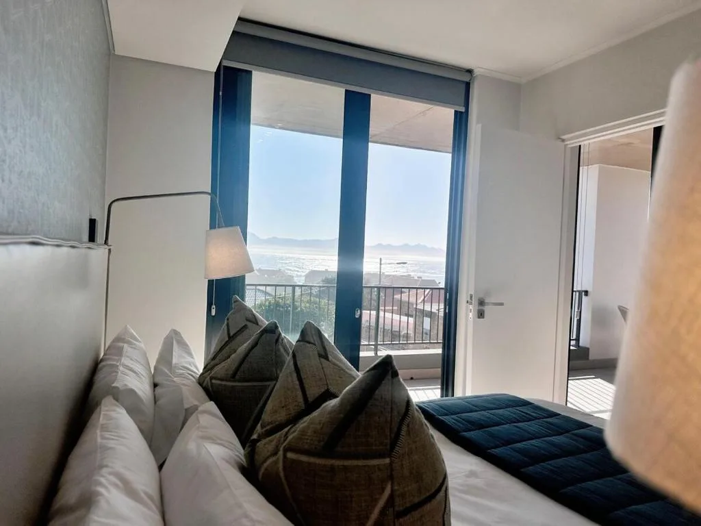 Bedroom with ocean and mountain views through floor-to-ceiling windows