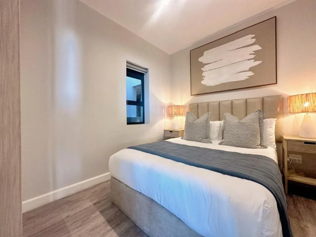 Modern bedroom with queen bed, upholstered headboard, bedside lamps, and wall art