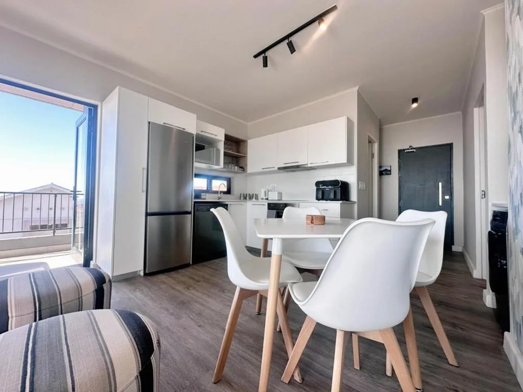 Modern open-plan kitchen with stainless steel appliances and white cabinetry