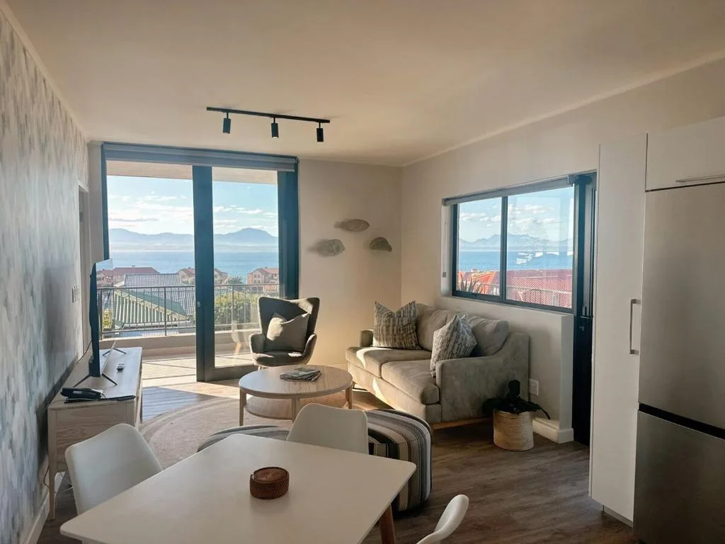 Bright lounge with coastal views, comfortable seating, and glass doors opening to deck
