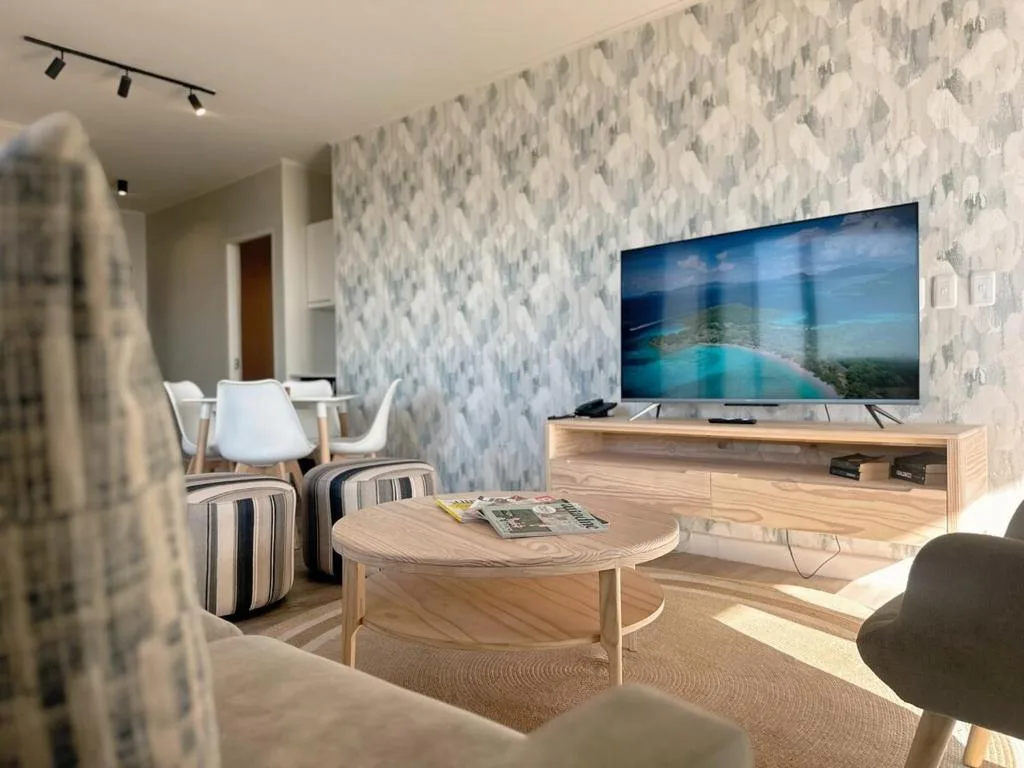 Modern lounge with TV, wooden furniture, and patterned wallpaper accents