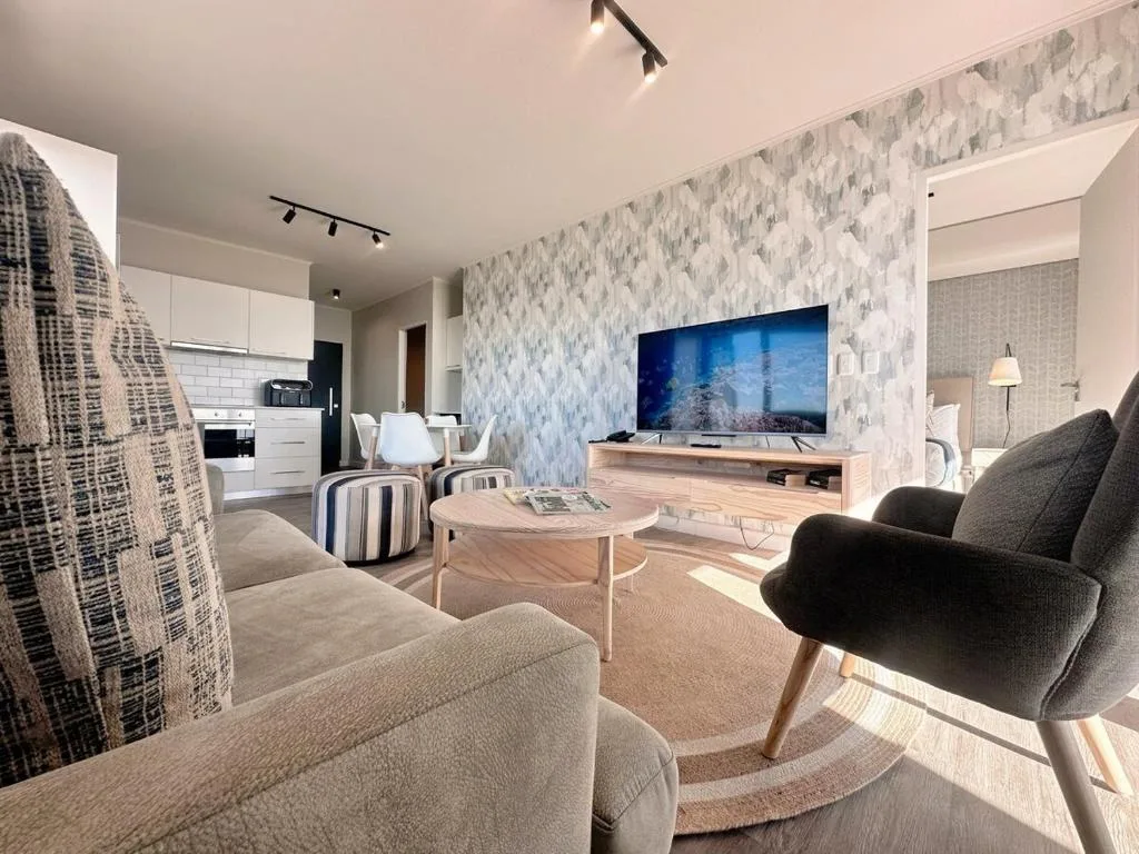 Modern lounge with sofa, TV, and open-plan kitchen area