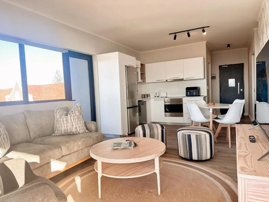 Open-plan lounge with sofa, round coffee table, and kitchen visible beyond