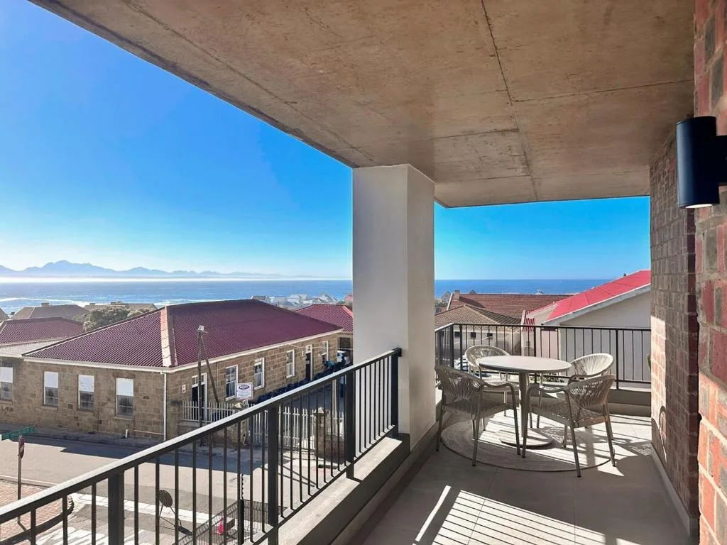 Scenic ocean and mountain vista from elevated balcony with seating
