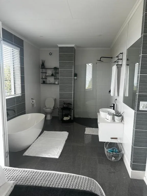 Modern bathroom with freestanding tub, walk-in shower, and dark tile accents