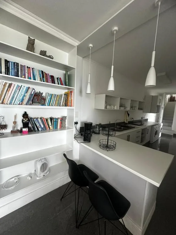 Modern white kitchen with open shelving, gas stove, and pendant lighting