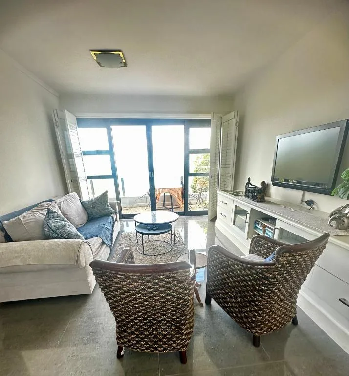 Bright lounge with comfortable seating, TV, and glass doors opening to deck