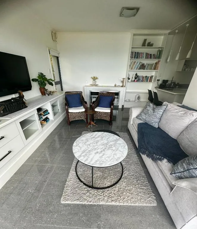 Modern lounge with sofa, armchairs, TV, and marble coffee table