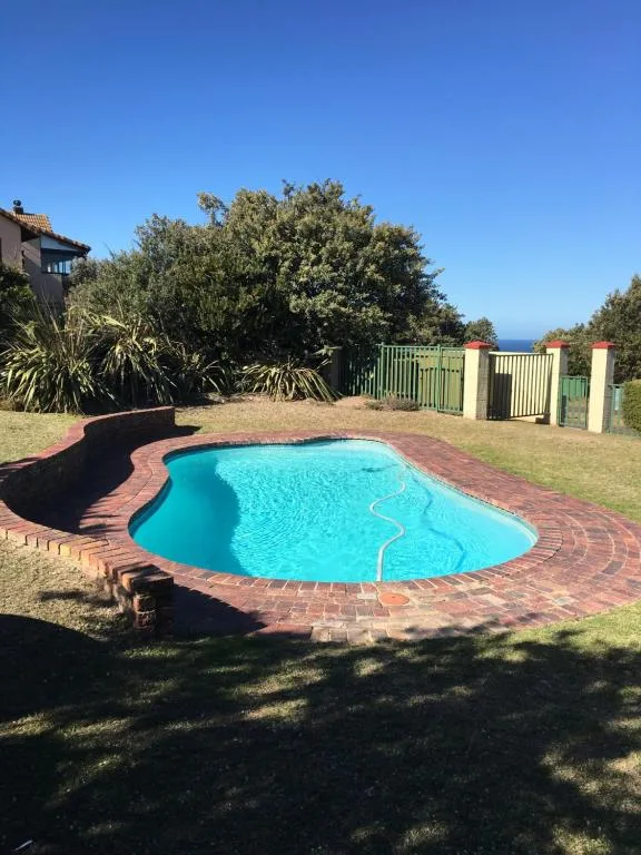 Turquoise kidney-shaped swimming pool with brick surround and garden views