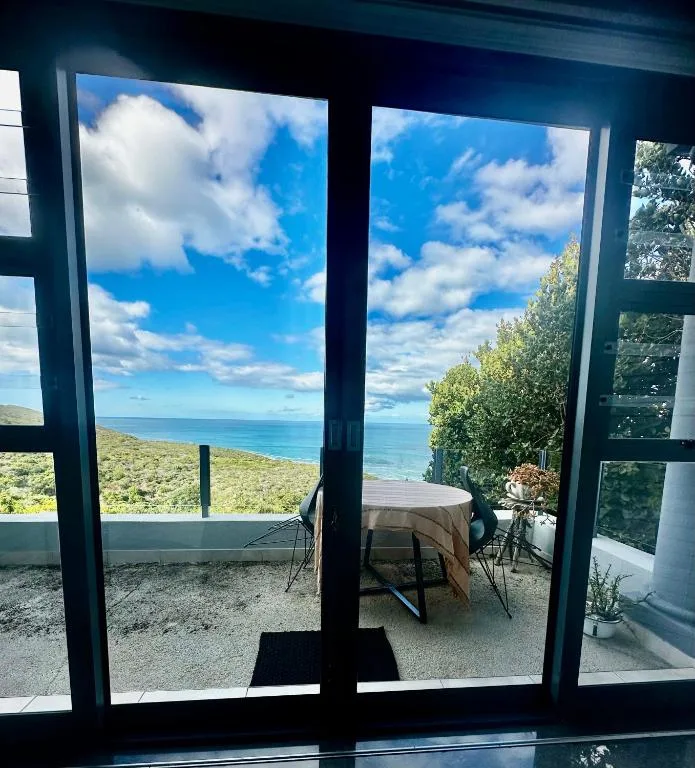 Ocean and coastline vista framed by open glass doors from deck