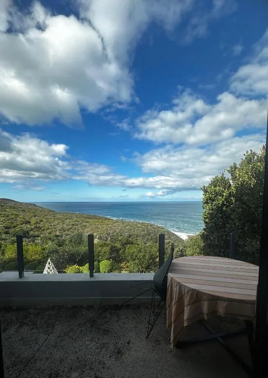 Expansive ocean and coastline vista from shaded deck with dining furniture