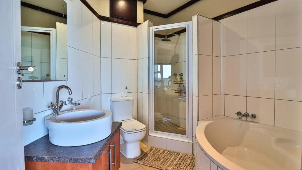 Modern bathroom with round sink, toilet, enclosed shower, and soaking tub