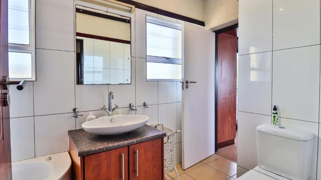 Modern bathroom with oval sink, wooden vanity, mirror, and toilet fixtures
