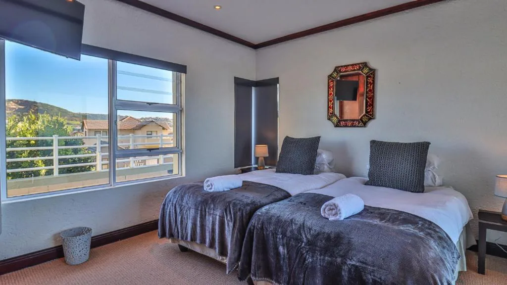 Bright bedroom with two beds, mountain views through large windows