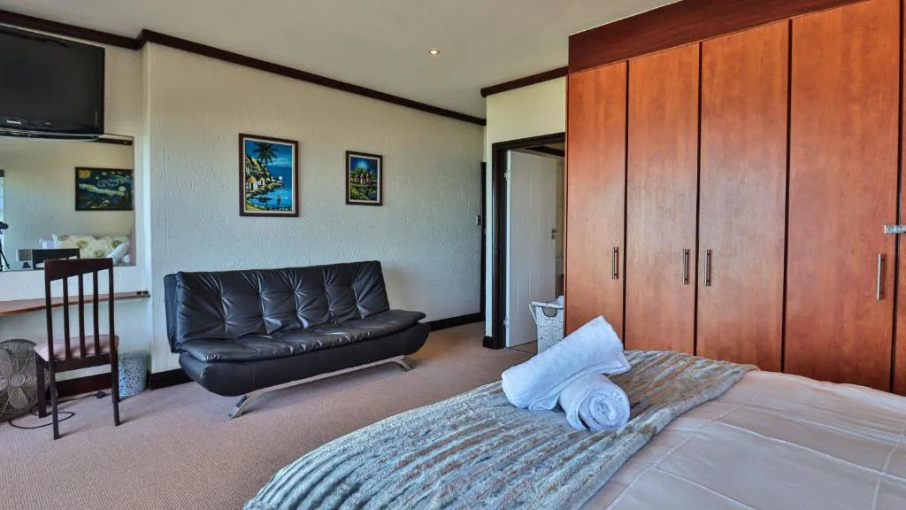 Spacious bedroom with queen bed, black sofa, and wooden wardrobe