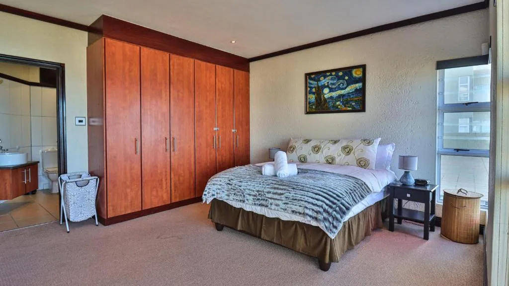 Spacious bedroom with queen bed, wooden wardrobe, and ensuite bathroom