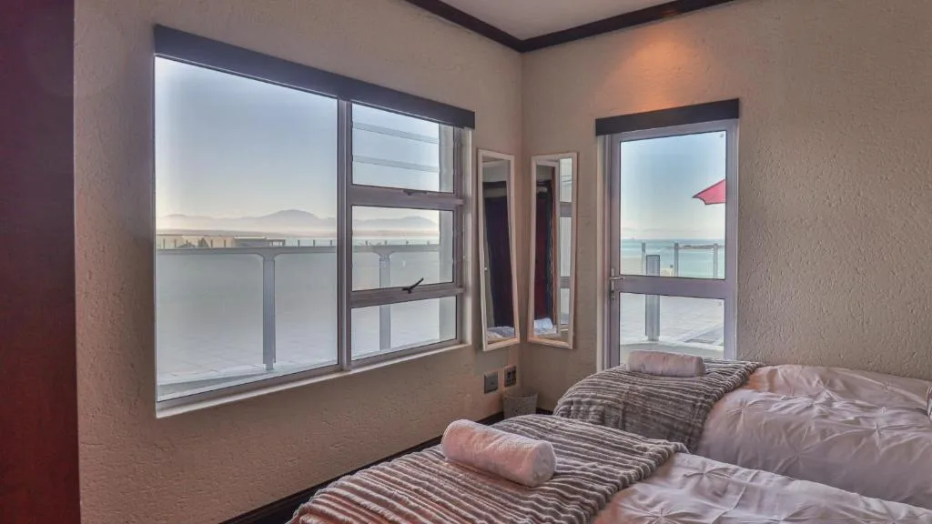 Bedroom with twin beds and expansive waterfront views through large windows