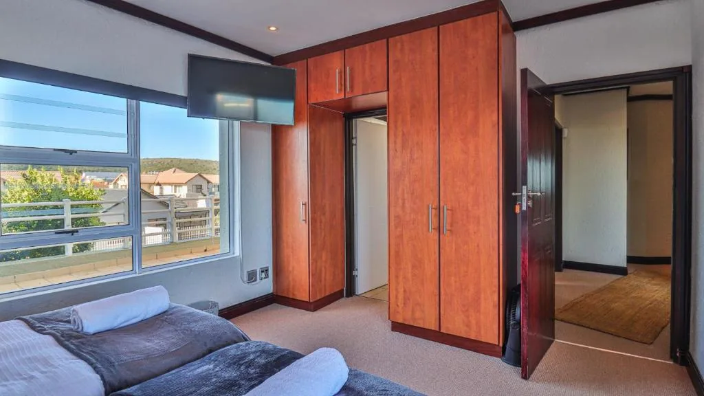 Spacious bedroom with wooden wardrobe and large window overlooking town