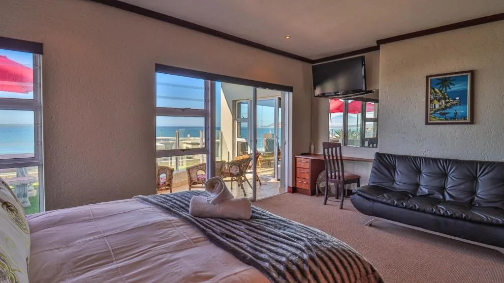 Spacious bedroom with ocean view through sliding doors and lounge area