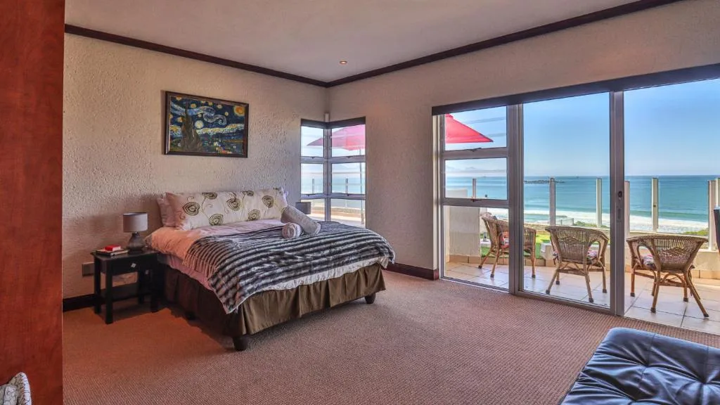 Spacious bedroom with ocean view through large glass doors and deck access