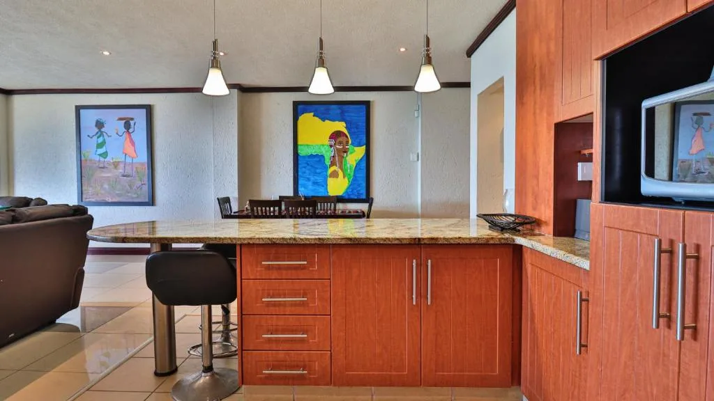 Modern kitchen with red wood cabinetry, granite countertop island, and pendant lighting